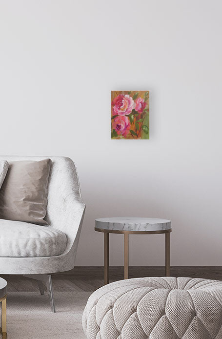 Floral painting on a wall above a gray armchair and ottoman in a room.