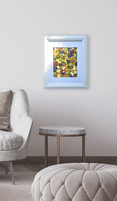 Framed abstract art piece on a wall above a chair and ottoman in a room.