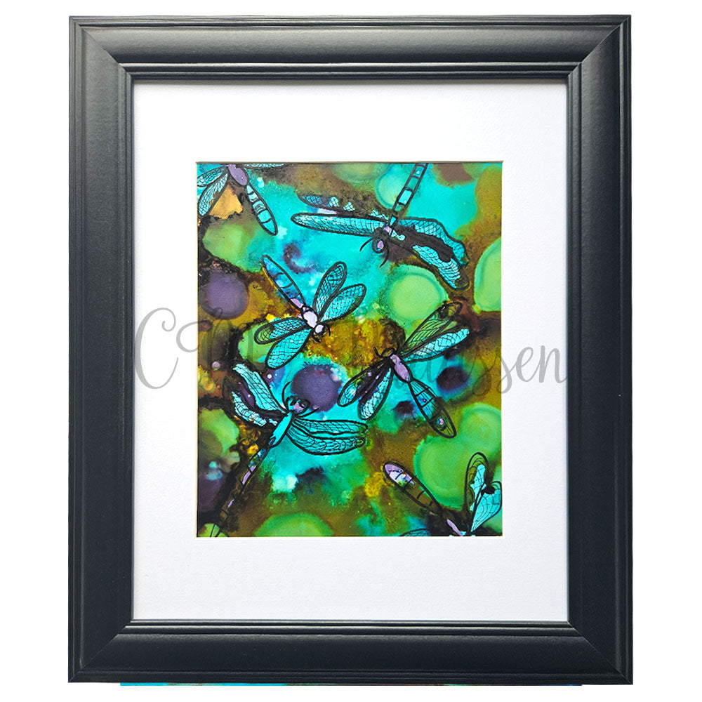 Framed artwork of dragonflies on a colorful abstract background