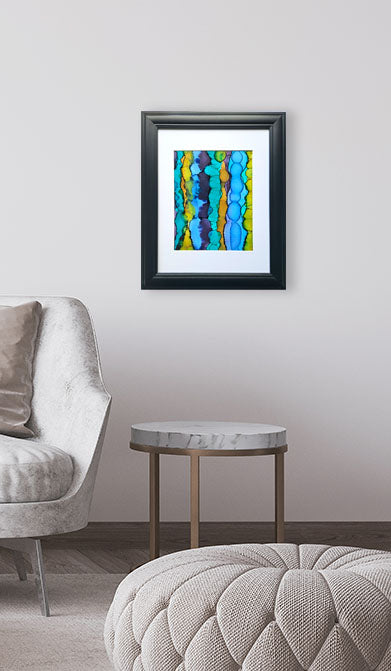 Framed abstract artwork on a wall above a round table in a living room setting.