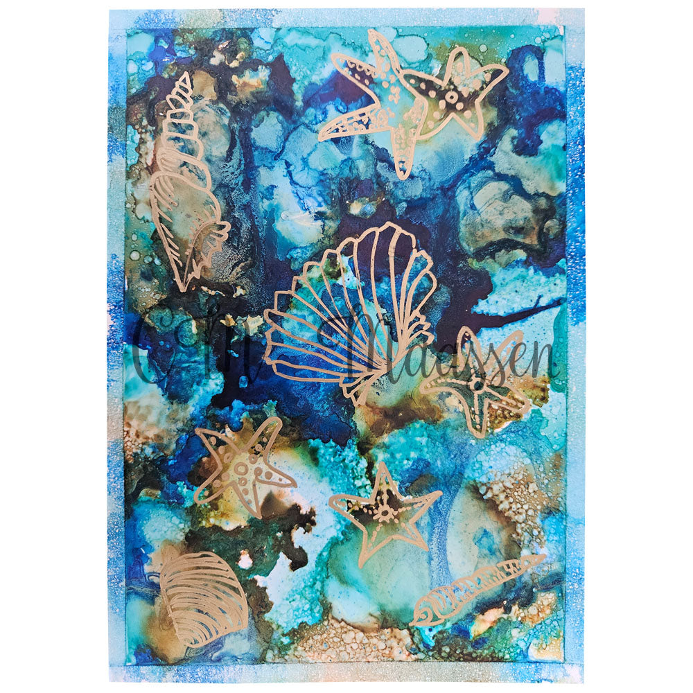 Decorative paper with gold sea-themed cutouts on a blue and green watercolor background