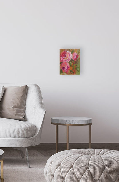 Floral painting on a wall above a gray armchair and ottoman in a room.